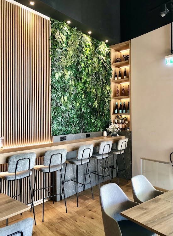 Moderner Innenraum des Café Apostel mit Pflanzenwand und Holzbar
